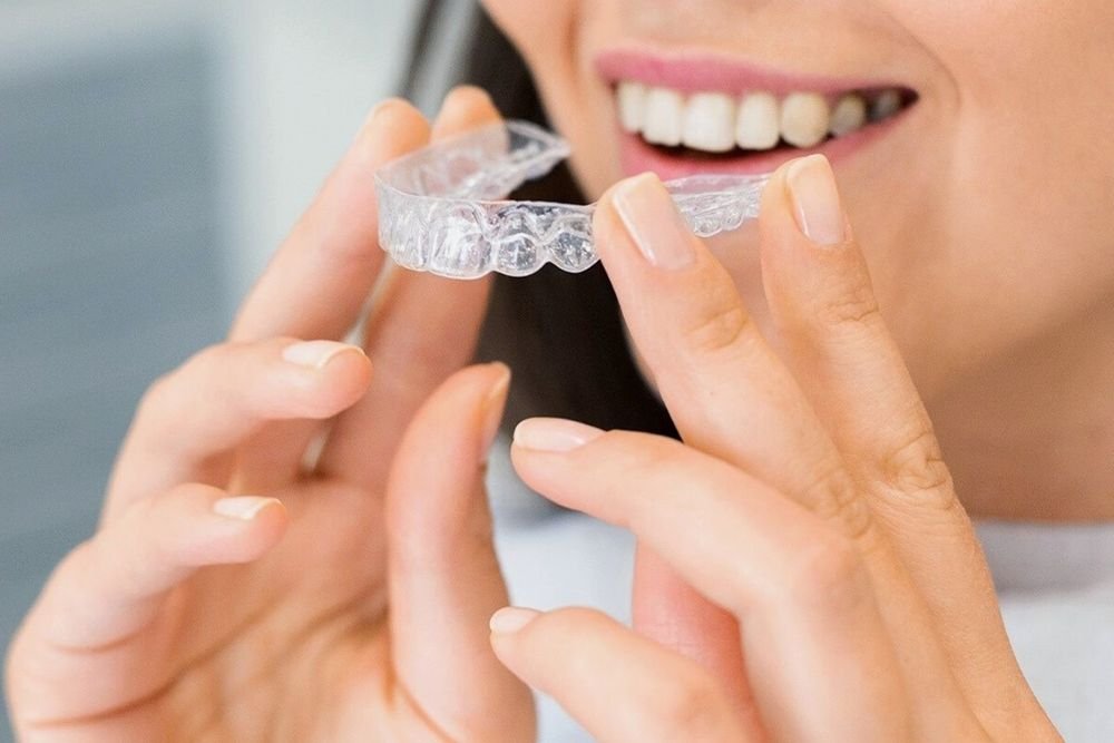 Paciente sosteniendo un alineador transparente de ortodoncia invisible
