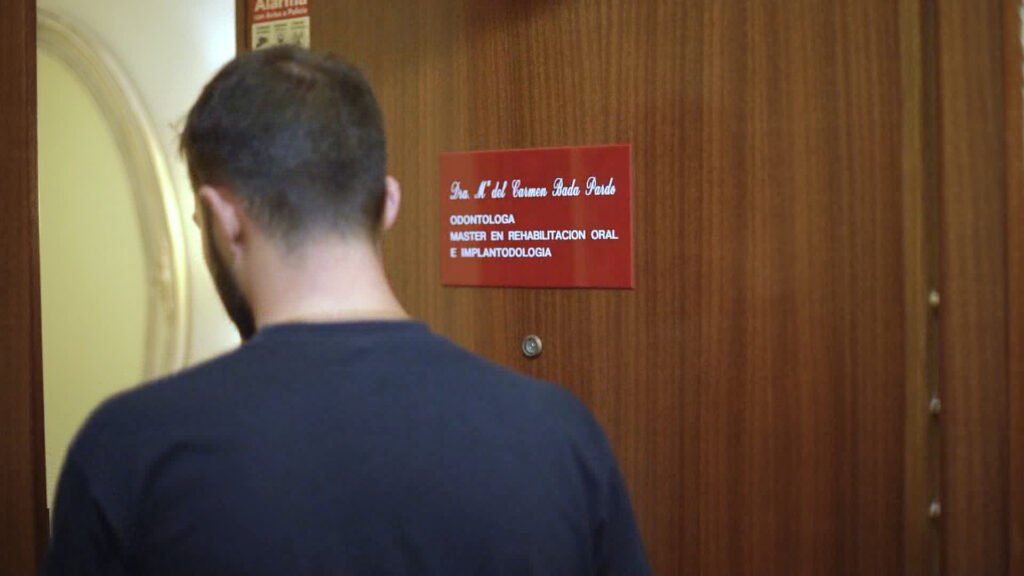 Paciente ante el rótulo de entrada del Centro Dental Dra. Bada Pardo